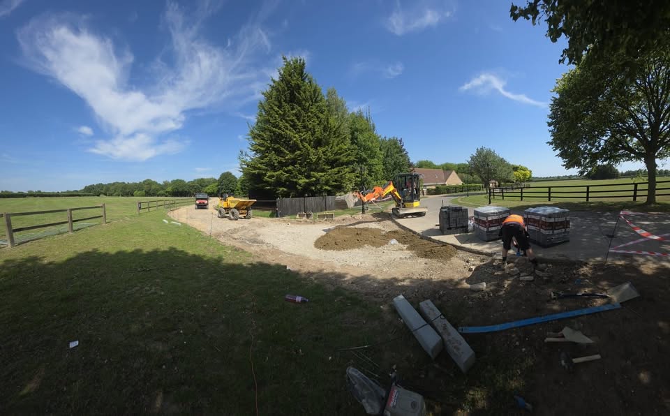 Groundworker laying block paving with mini digger and dumper on site