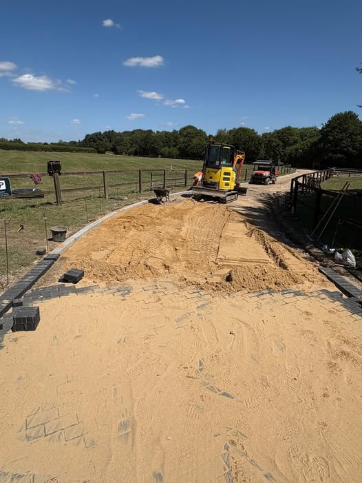 Excavator preparing a driveway sub-base on a rural plot